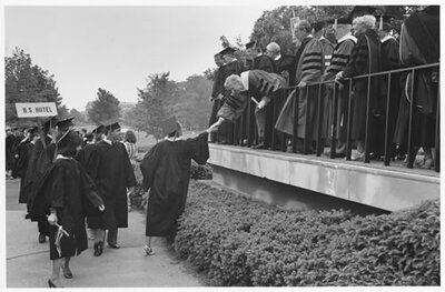 Frank Rhodes shakes the hand of a graduating senior at commencement