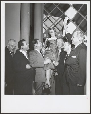 Dr. Brothers waves a check for $64,000, December 1955, while being held on the shoulders of former boxing champs Gus Lesnevich (left) and Bob Olin. Looking on are former champ Mickey Walker (second from right) and Colonel Edward Eagan, former Olympic boxing champion and former New York State boxing Commissioner.