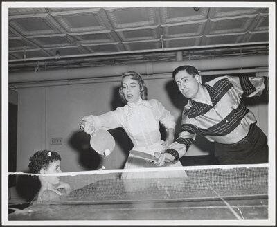 Joyce and Milton playing ping-pong as Lisa looks on, circa 1956-1958.