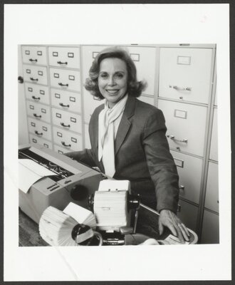 Photograph of Dr. Brothers in front of her many filing cabinets, circa 1980.